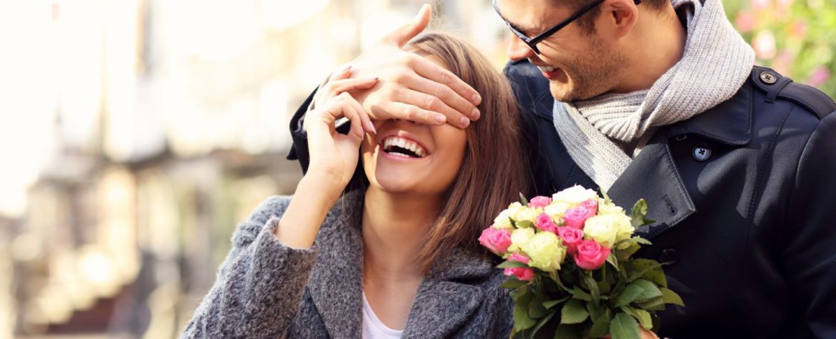 Young romantic couple, man surprising woman with flowers