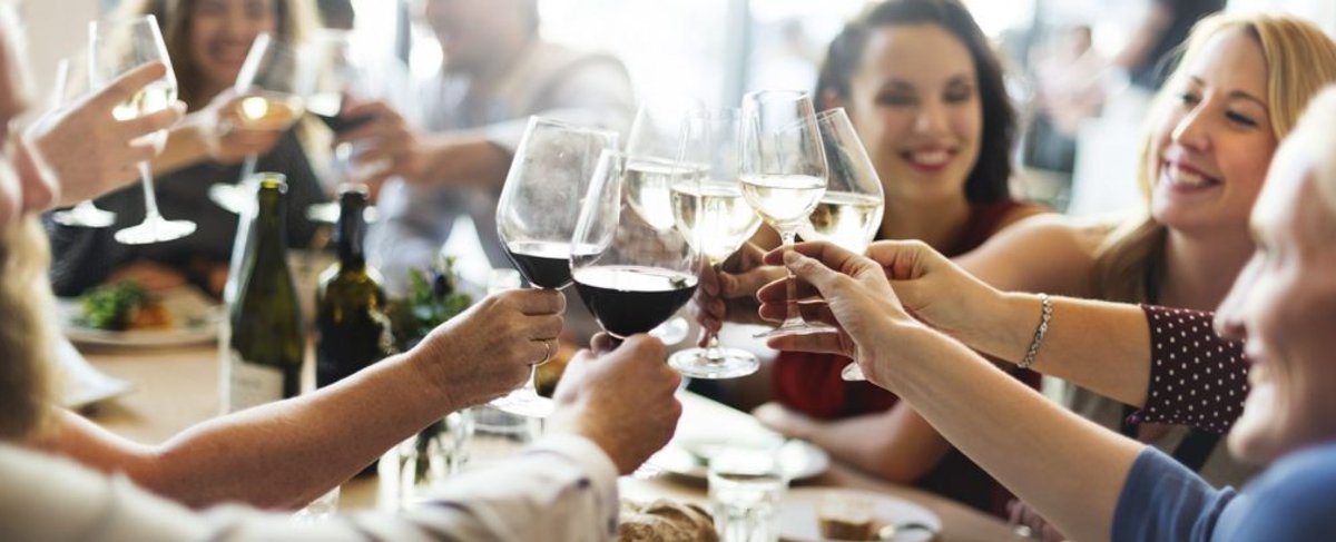 group of people of different ages around a restaurant dining table clinking wine glasses